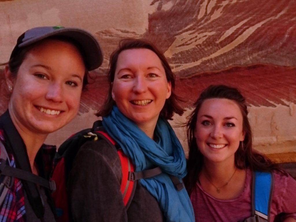 Wissenswertes Jordanien, Sicherheit in Jordanien, Wandern in der Gruppe. 3 Frauen lächeln in die Kamera vor marmorierten Steinen in Petra, Jordanien