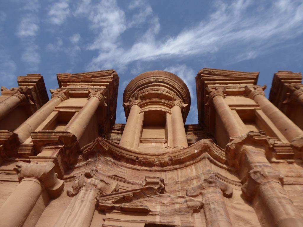 Fassade des Klosters in Petra, Jordanien, Blick von direkt unten. Blauer Himmel mit dünnen weißen Wolken. Reiseführer Jordanien