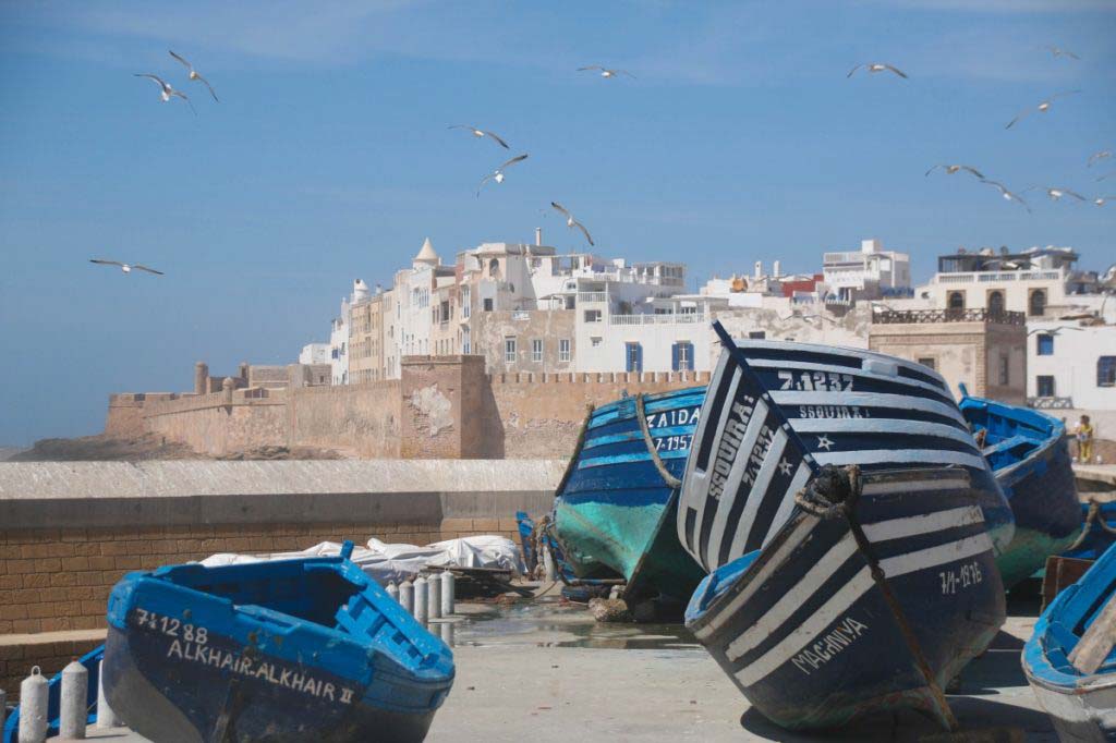 fishing boats in front of fortified city