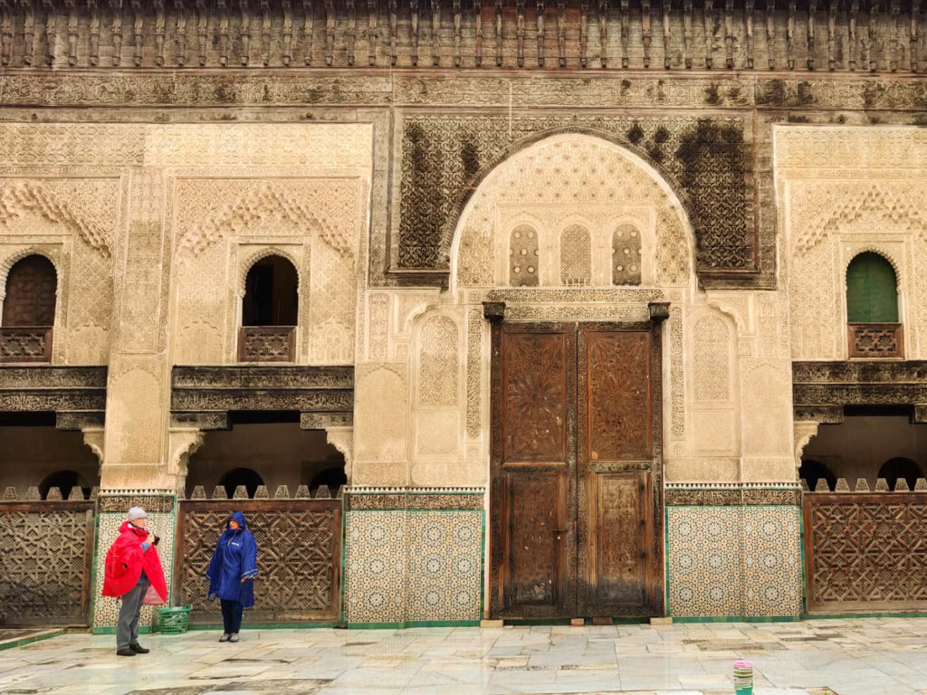 2 Menschen in Regenjacken in Innenhof der Medersa Bou Inania in Fes, beste Reisezeit Fes