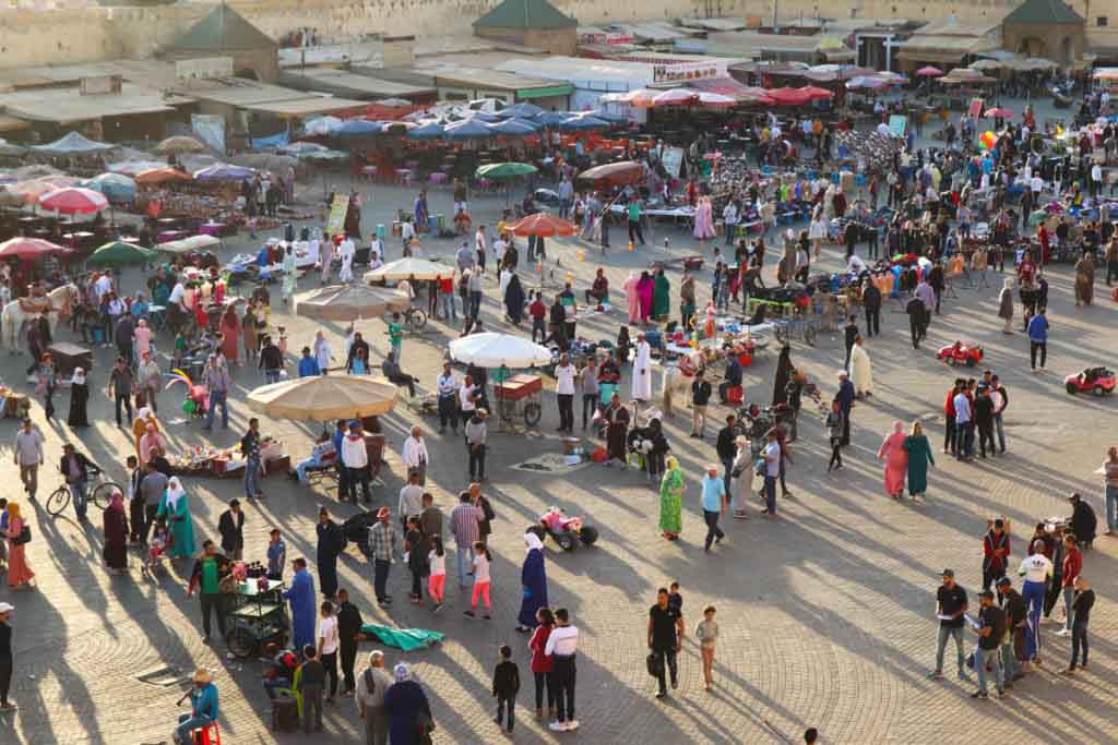 viele Menschen auf Platz mit Sonnenschirmen, Saftständen und Verkäufern, Place el Hedim in Meknes, Meknes Reiseführer