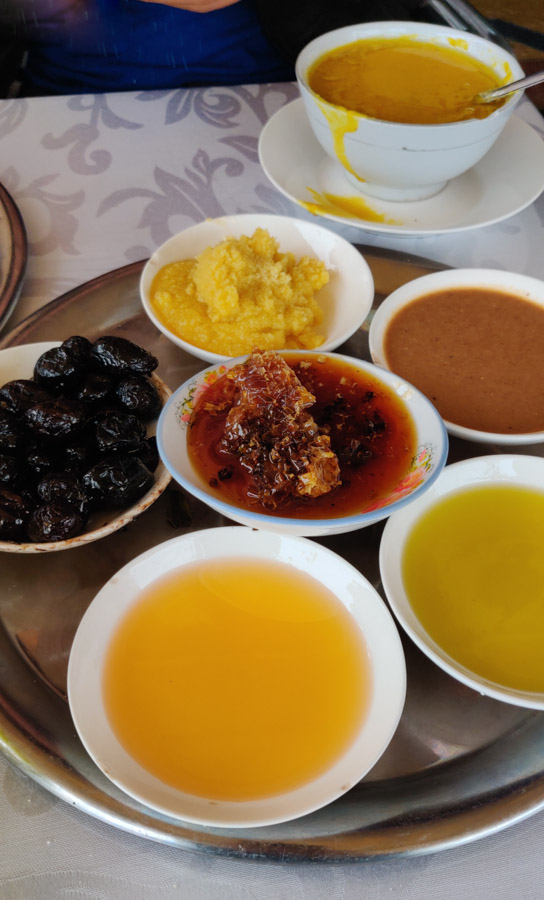 Best breakfast in Essaouira, small dishes with argan oil, olive oil, amlou, honey, butter and olives. Bowl of bissara, bean soup