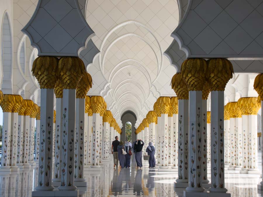 Viele Säulen, mit Blumenmosaik und Gold verziert. Durchgang mit Bögen, weiter hinten im Bild Familie im Durchgang. Abu Dhabi, Scheik Zayed Moschee, die wohl schönste Moschee die man als nicht-Muslim besuchen darf