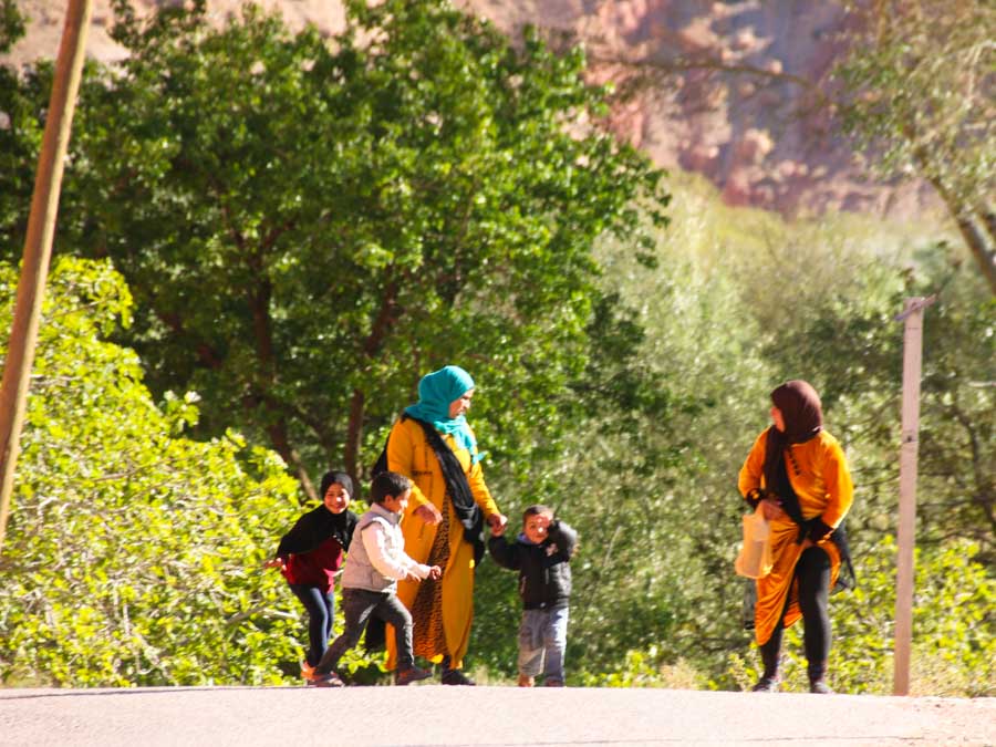 2 women with 3 children walking the street surrounded by trees. Women in Morocco