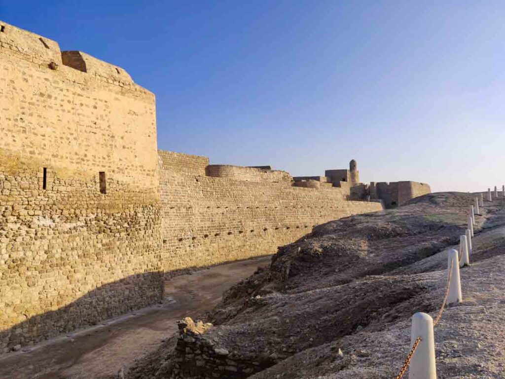 Huge stone walls of the Bahrain fort at sunset, one of the best things to do in Bahrain