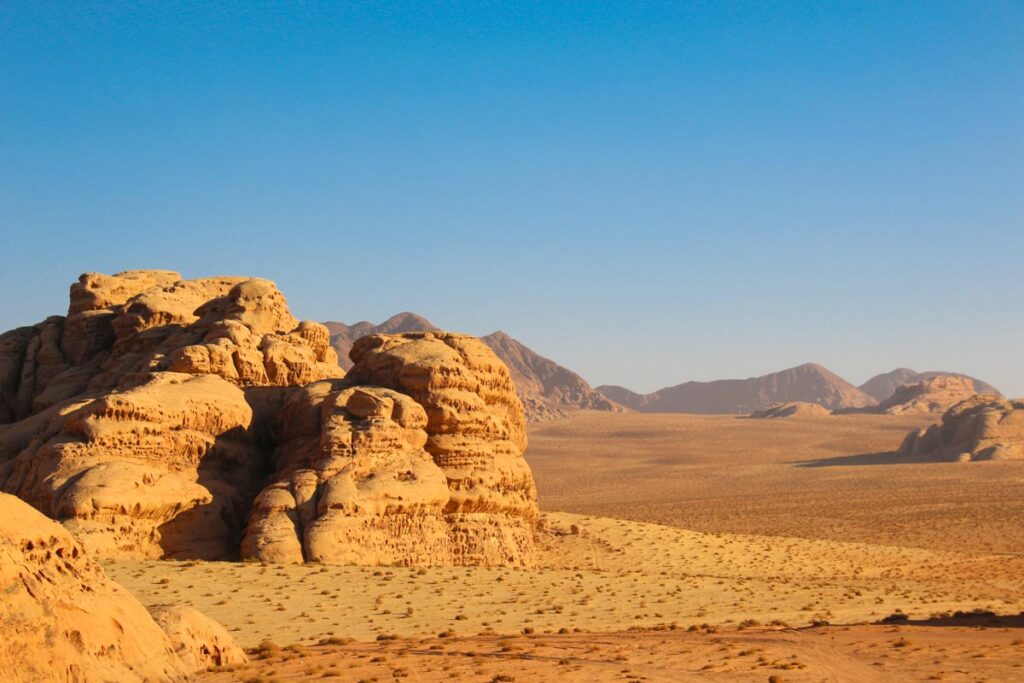 Wadi Rum Jordan, wide valley with red sand and sandstone rock formations in the distance